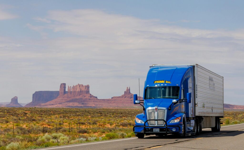 pexels-photo-27508769-27508769 A blue truck travels on the highway with Monument Valley's iconic mesas in the background.
